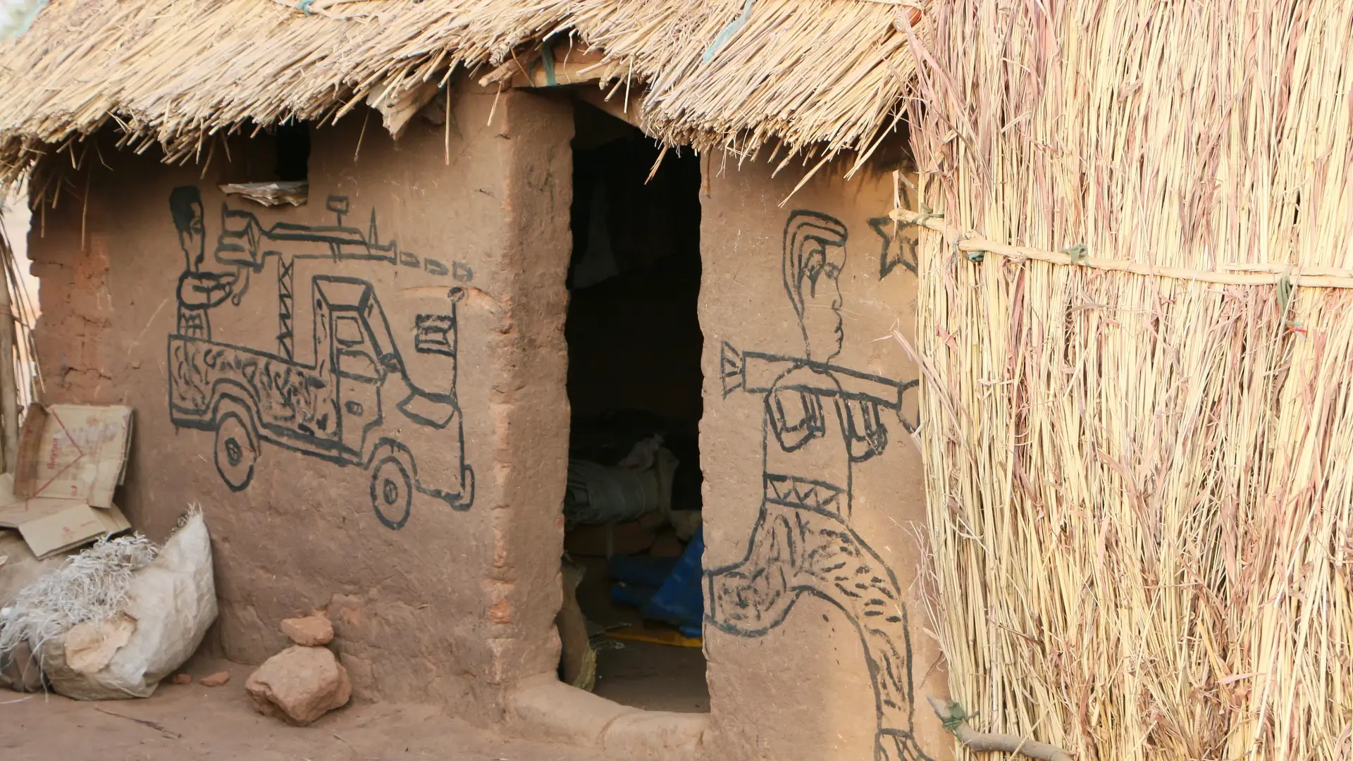 Crianças desenham cenas de guerra nas paredes em um campo de deslocados do Sudão