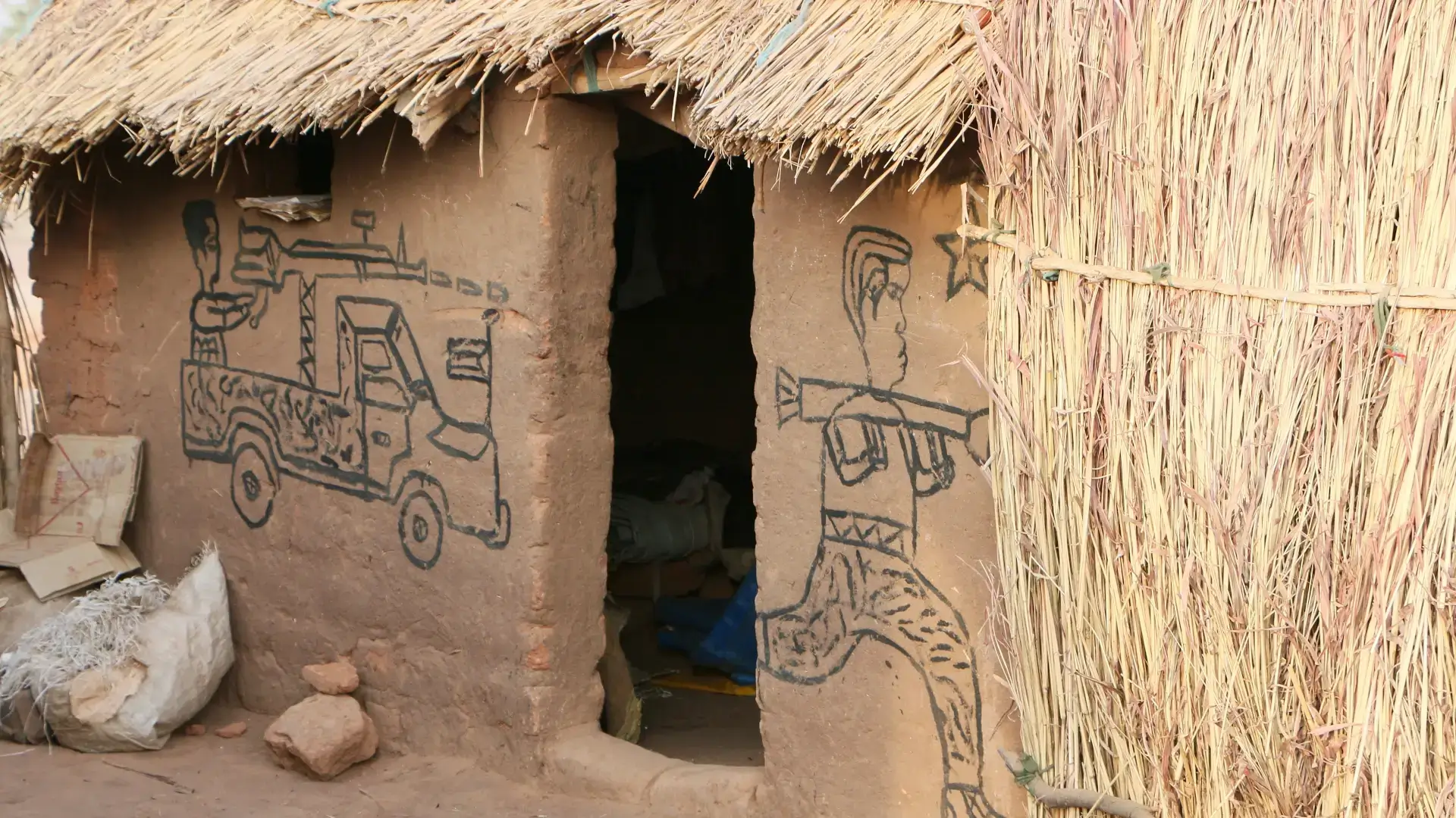 Niños dibujan escenas de guerra en las paredes de un campo de desplazados en Sudán