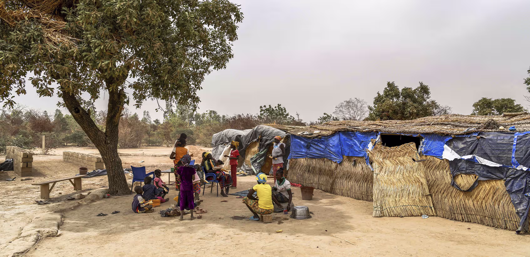 Famílias em frente a abrigo feito com palha e lonas em Burkina Faso